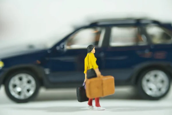 Traveling people with luggage, cars in the background, miniature figures scene