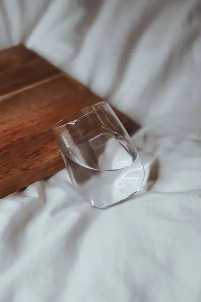 Colpo Verticale Bicchiere Acqua Con Una Tavola Legno Tessuto Bianco — Foto Stock