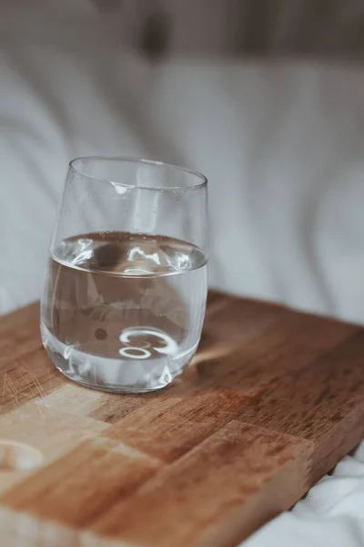 Eine Vertikale Aufnahme Eines Wasserglases Mit Einem Holzbrett Auf Weißem — Stockfoto