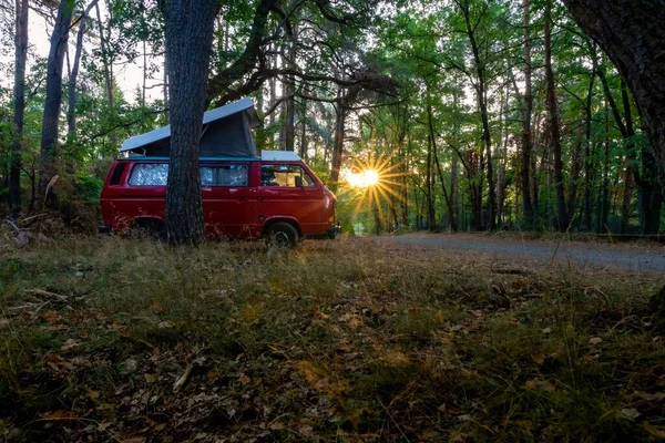 Una Caravana Roja Estacionada Sideroad Bosque Con Vigas Atardecer Atravesando —  Fotos de Stock