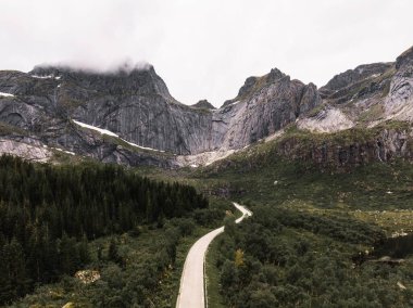 Soluk kesici kayalık tepelerin arkasındaki yeşil tarlada bir otoyol manzarası.
