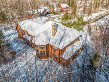 Dağlarda karla kaplı çağdaş bir kır evinin havadan görünüşü.