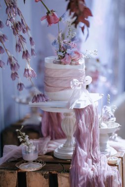 Çiçekli bir düğün pastası. Masasında pembe bir fiyonk var.