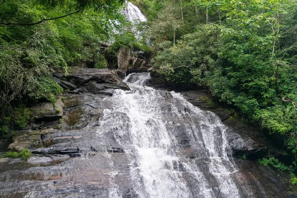日光の森の緑に囲まれた岩の上の小さな滝 — ストック写真