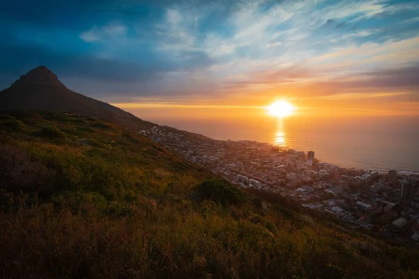 stock image A gorgeous view of a mountainside town in Africa overlooking the calm sea at sunrise under an orange sky