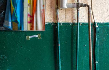 Boruları, küçük bir aynası ve küçük bir notası olan eski yeşil bir duvarın yakın çekimi.