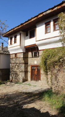 Güneşli bir günde mavi gökyüzünün altındaki küçük bir köyde eski bir kır evinin dikey görüntüsü.