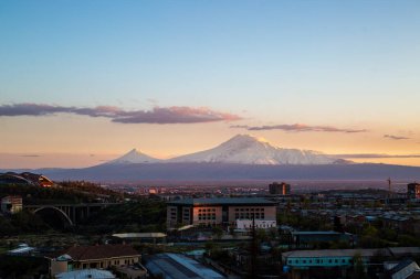 Arka planda Ararat Dağı 'nın karlı zirveleriyle Erivan şehrinin güzel bir gün batımı manzarası.