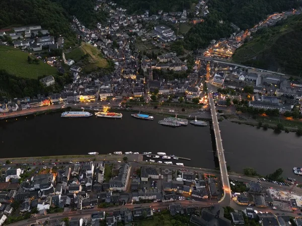 ライトアップされた街と夕暮れ時の川に架かる橋 — ストック写真