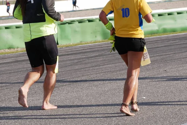 Selektivní Snímek Dvou Lidí Běžících Bosý Maraton Asfaltové Cestě — Stock fotografie