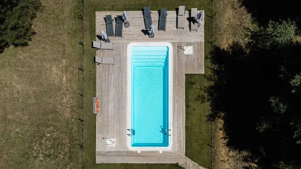 stock image An aerial view of swimming pool with wooden deck and lush green trees nearby