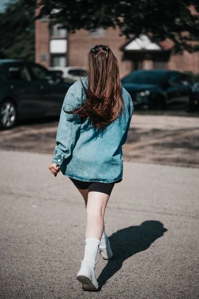 ジーンジャケットを着た白人のカジュアルな女の子のバックショットと通りを横断する短い — ストック写真
