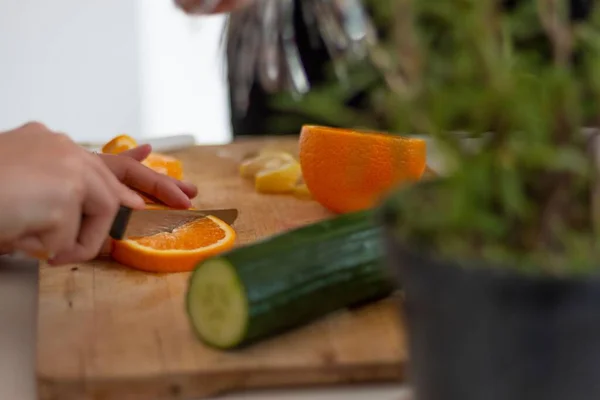 キッチンのまな板にオレンジとキュウリを切るシェフのクローズアップ — ストック写真