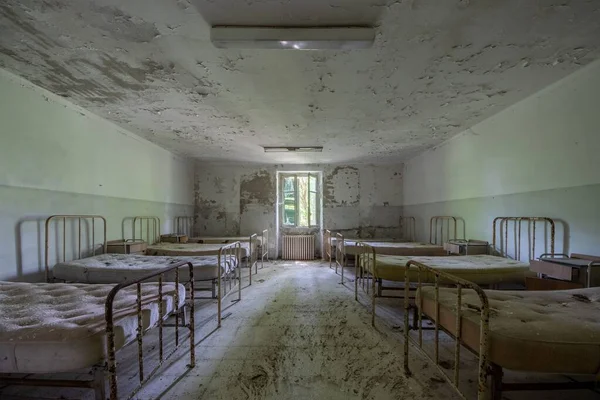 一间废弃破旧不堪的医院 有许多床 背景上有窗户 — 图库照片