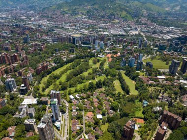 Medellin, Kolombiya 'daki El Poblado şehrinin arka planında yeşil tepelerle çekilmiş bir fotoğrafı.