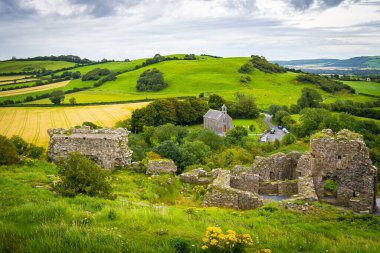 Yeşil dağların üzerindeki bulutlu gökyüzü dolambaçlı bir yol ve uzak bir şapel.