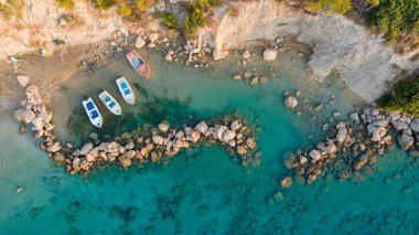 Güneşli bir günde gemileri olan kayalık bir körfezin havadan görüntüsü.