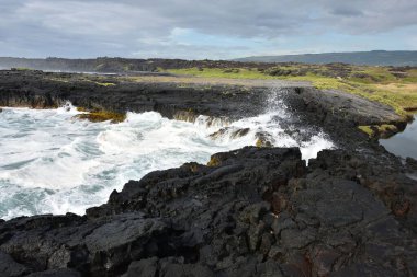 Yeşil tarlalarla çevrili akan kayalık bir nehir.