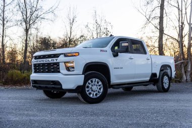 Beyaz Chevy Silverado 2500 etrafını ormanlarla çevirmiş.