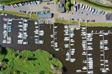 Ortasında nehir ve liman olan küçük binaları ve tarlaları olan bir şehrin havadan çekilmiş görüntüsü.
