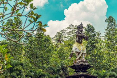 Bali 'deki yemyeşil bir parkta antik bir Bali heykeli.