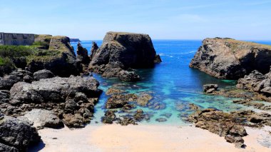 Parlak güneş ışığı altında kayalık bir sahilin manzarası