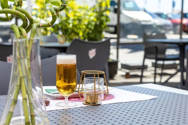 晴れた日には 地元の屋外カフェでテーブルに置かれたビールと装飾用のキャンドルのガラス — ストック写真