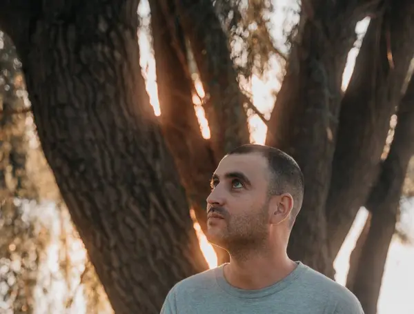 Καυκάσιος Άντρας Ακουμπά Στα Δέντρα Κοιτώντας Στον Κήπο Ηλιοβασίλεμα — Φωτογραφία Αρχείου