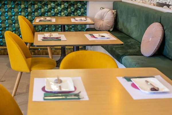 緑のソファと花のプリントの壁を備えた地元のカフェの居心地の良いインテリア — ストック写真
