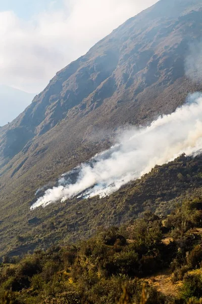 stock image A vertical shot of large plumes of fire smoke on top of a mountain in the Peruvian Andes