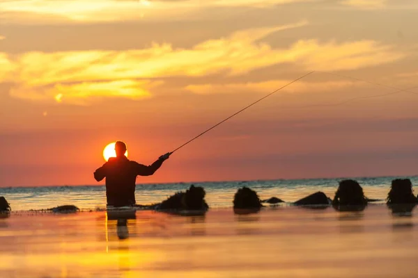 Güneş Batarken Bulutlu Gökyüzüne Karşı Denizde Dikilirken Oltayla Balık Avlayan — Stok fotoğraf