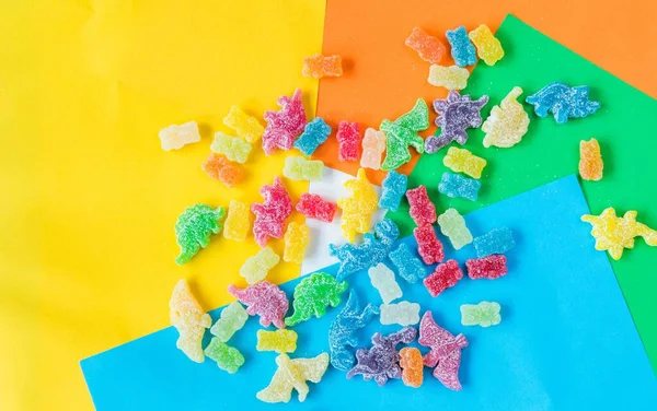 一种扁平的 五彩缤纷的糖果 形似恐龙 背景五彩斑斓 熊身上涂满了酸性粉末 — 图库照片