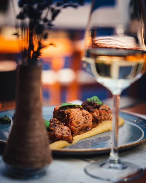 一个精选的烤鲑鱼焦点 桌上放着一杯白葡萄酒和一个花瓶 — 图库照片