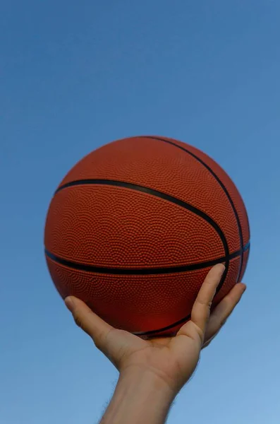 Крупный План Красного Баскетбола Руках Человека Ясным Голубым Небом — стоковое фото