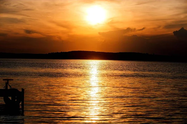 背景に丘のシルエットが見える湖の上の壮大な夕日のシーンの景色 — ストック写真
