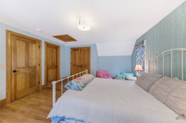 İçinde yeşil duvarlar, ahşap zemin ve kapılar olan bir yatak odası..