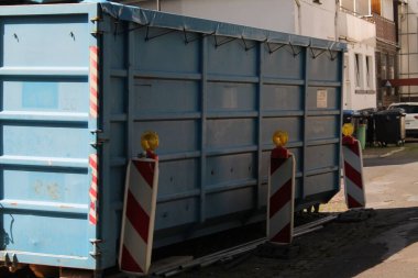 Güneşli bir günde şehrin ortasında metal bir çöp konteynırı