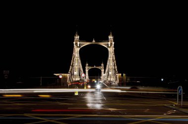 Londra 'daki ikonik Albert Köprüsü' nün ışıkları açık ve uzun pozlu bir gece çekimi.