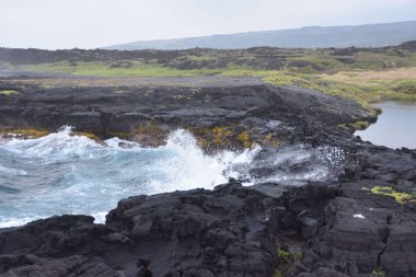 Yeşil tarlalarla çevrili akan kayalık bir nehir.