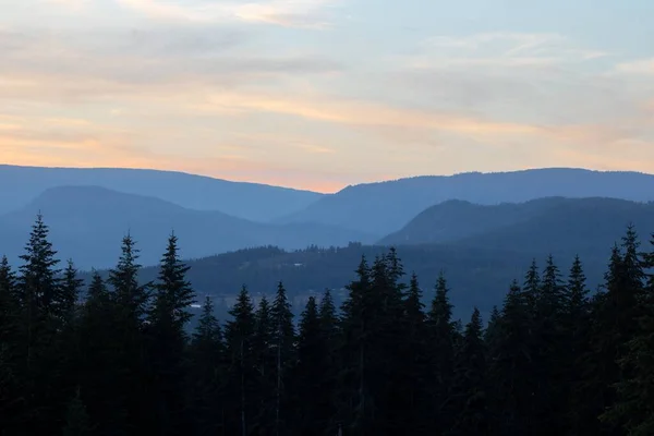 Gün Batımında Yüksek Dağların Önünde Bir Orman Arkasında Bulutlu Bir — Stok fotoğraf