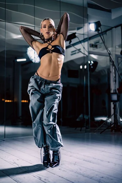 縦長のショットの美しい女性ダンサーポーズでメッシュオーバーレイ作物上で黒とバギーパンツ — ストック写真