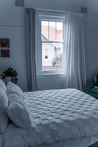 明るい窓の外には 白い寝具 緑の植物 オレンジの家の景色が見えるモダンなベッドルーム — ストック写真