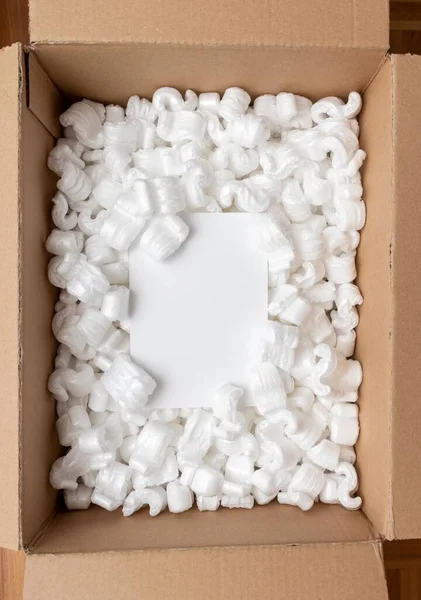 Een Kartonnen Doos Gevuld Met Piepschuim Pellets Witte Kaart Kopieerruimte — Stockfoto