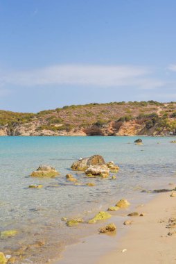 Sahile yakın denizde kayaların dikey görüntüsü ve mavi gökyüzünün altında bir uçurum.