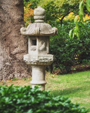 Güneşli bir günde, Japon bahçesindeki güzel taş yapının dikey bir görüntüsü.