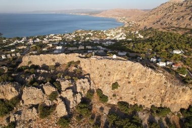 Arka planda mavi gökyüzü olan kayalık sahildeki bir kasabanın havadan görünüşü, Rodos, Yunanistan