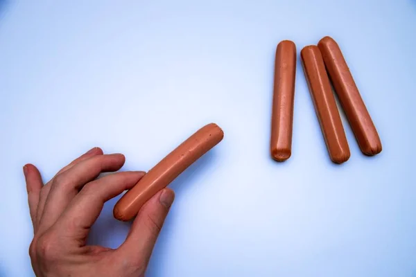 Closeup Person Hand Next Raw Sausages Isolated Blue Background — Stock Photo, Image