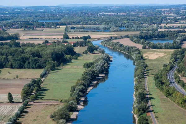農地や緑の植生に囲まれた農村部を流れる川の上からの眺め — ストック写真