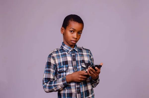 紫色の背景に携帯電話を持っている有料シャツの少年 — ストック写真