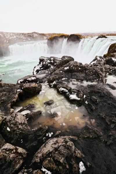 アイスランドの岩の近くの美しい滝の垂直ショット — ストック写真